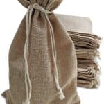Natural jute bags with drawstring closure beside a stack of flat jute sacks