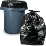 Household bin fitted with a garbage-bag liner beside a tied black waste bag